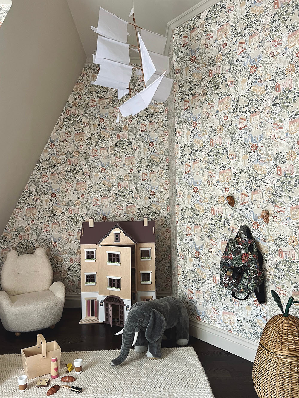 barnrumsinspo med tapet. Gulligt barnrum med teddy fåtölj, dockhus, takdekorationer och förvaring för leksaker