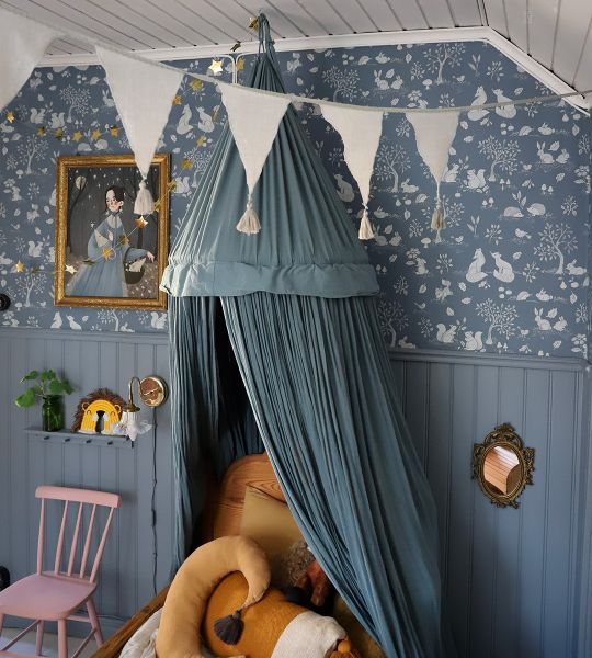 blå barntapet med söta små djur som möts av blå pärlspont. Blå sänghimmel med vita vimplar i taket.