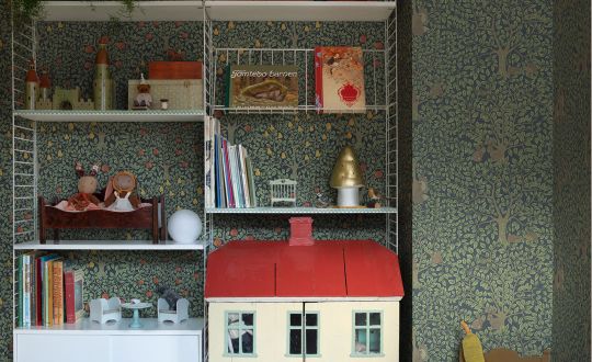 grön tapet till barnrum. Vit stringhylla med dockhus och gunghäst i trä.